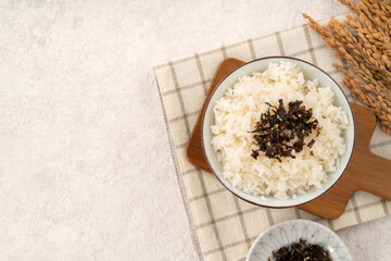 A bowl of white rice topped with seasoned seaweed and white sesame.