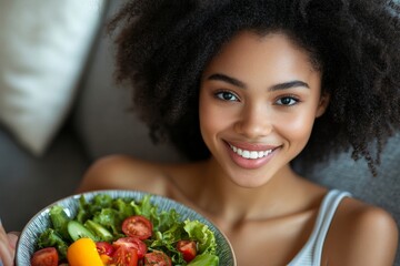 Portrait of a young woman sitting at home on the sofa with a laptop, eating salad and fresh vegetables from a plate, smiling at the camera, Generative AI