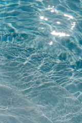 Swimming pool with clear blue water with sunlight shadow reflections. Minimalistic aesthetic summer vacation concept background	