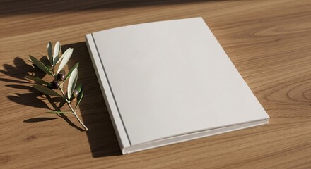 Fototapeta premium Blank white book on a wooden table with olive branch
