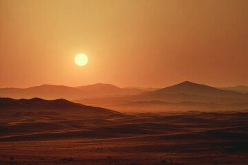Fototapeta premium Wide desert landscape with glowing sun setting behind distant dunes, warm golden orange gradient sky