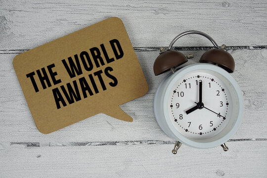 Naklejki The World Awaits text with alarm clock on wooden background