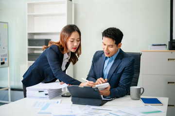 Asian businessman and woman workers talking on the smartphone and using laptop Professionals in Teamwork Finance, Marketing