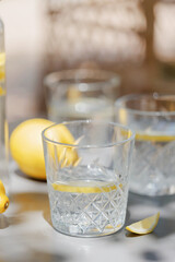 Glassware with lemon slices and fresh lemons arranged on a table in soft dappled light, perfect healthy summer refreshment