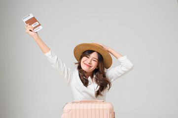 A cheerful traveler holds a passport and smiles broadly, showcasing excitement for an upcoming journey with a suitcase beside her.