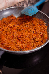 Mince meat with chopped carrots and homemade tomato sauce cooking on frying pan on induction stove. Cooking delicious dish with fresh mince meat, vegetables and tomato sauce at home.