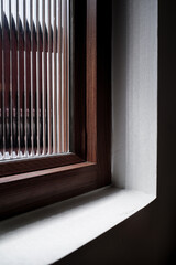 Close-up of a modern wooden window frame with ribbed textured glass