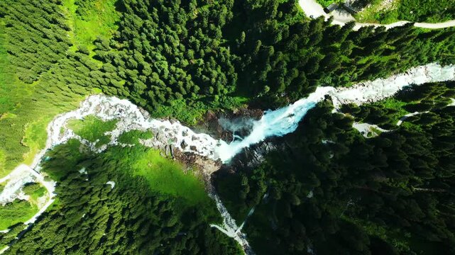 Aerial view of the Krimml Waterfalls cutting through lush green forests, creating a stunning contrast of color and texture, Krimml, Salzburg, Austria.