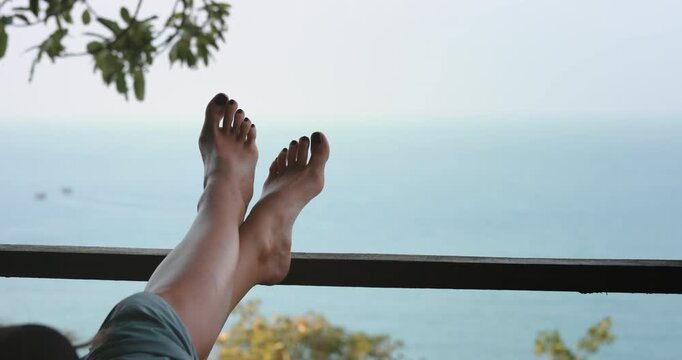 A person laying down with their feet raised up in the air, as if they are relaxing and stretching.