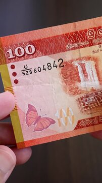 Vertical macro shot of man's hands and Sri Lanka rupee (LKR) banknotes. Concept of saving money for retirement, cash settlement, financial success, literacy and income planning in Sri Lanka.