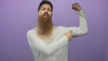 Man flexes bicep muscle in studio with index finger pointing to peak and clenched fist and...