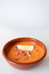 Spanish salmorejo decorated with serrano ham and boiled egg in a clay bowl
