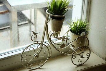 A small bike turned into a planter sits on a windowsill, great for home decor or gardening inspiration
