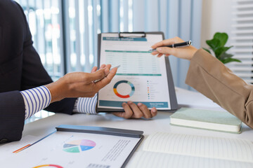 Business colleagues are engaged in a financial meeting, reviewing colorful charts and reports. They exchange ideas, make notes, and analyze strategies to achieve effective results.