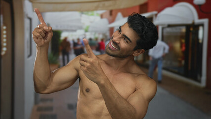 Man with bare chest smiling broadly and pointing finger on busy city street under morning sunlight;...