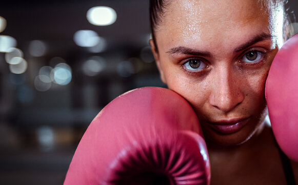 Close up portrait of female boxer in guard position with gloves looking at camera. - Powered by Adobe