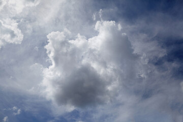 Obraz premium Fluffy white clouds scattered across a bright blue sky, creating a serene atmosphere with soft sunlight illuminating the scene, perfect for nature and weather themes