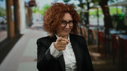 Woman in a suit making a vigilance gesture on a city street, conveying a sense of awareness and...