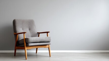 A stylish gray upholstered armchair with wooden frame sits in a simple, muted gray room.