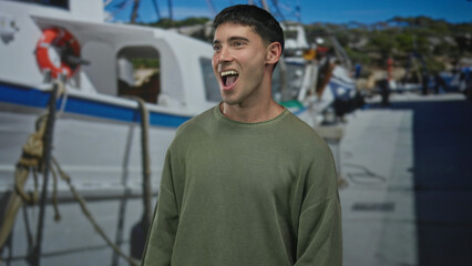 Fototapeta premium Hispanic man standing smiling and looking at camera by docked white boats at sunny crowded port pier; relaxation.