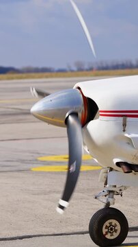 Front part of white aircraft with red lines. Little plane with rotating propeller. Vertical video
