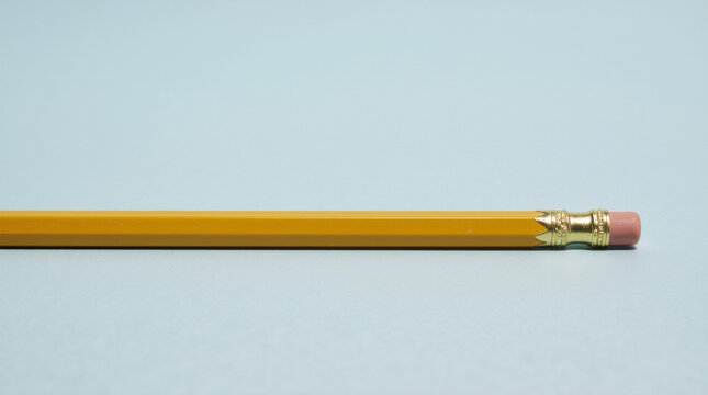 Yellow pencil with pink eraser flat on blue background minimal school stationary