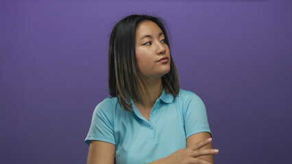 Obraz premium Woman wearing blue shirt looks thoughtful against a vibrant purple background, highlighting her pensive expression and surrounded by minimalistic isolated setting.