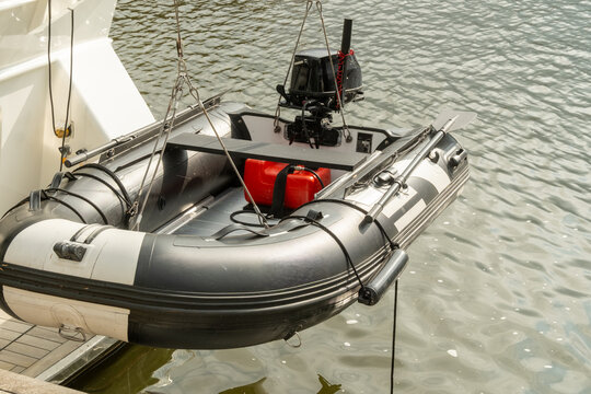 Inflatable dinghy hanging from davit crane system on yacht