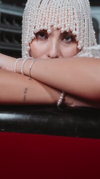 Young stylish woman in fashionable pearl headwear poses in an empty theatre looking seductively at the camera.