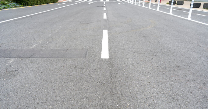 Freshly painted road with white dashed lane markings on smooth asphalt