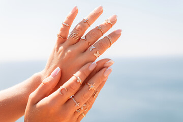 A woman is holding her hands up with a variety of rings on her fingers