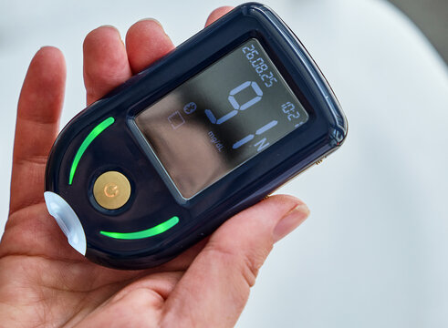 Close up modern Glucose Meter Showing Blood Sugar Result in Hand