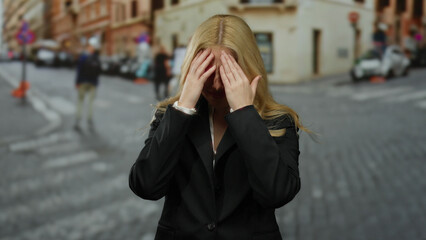 Fototapeta premium Woman standing outdoors in a bustling city street, appearing worried and contemplative, embodying urban emotion and stress in a crowded environment.