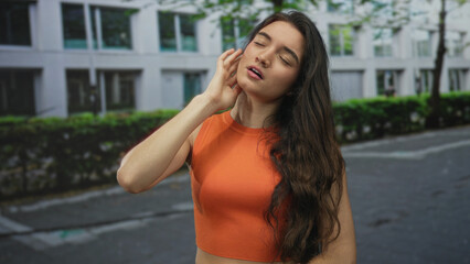 Woman pressing cheek with hand for toothache on a busy city street on concrete pavement; discomfort.
