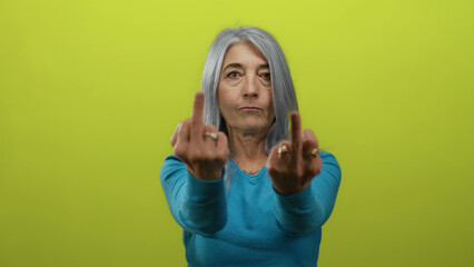 Senior grey-haired woman making an obscene gesture with both middle fingers raised, standing...