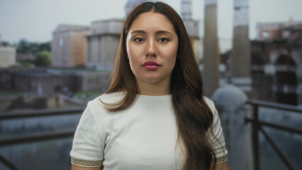 Young hispanic woman in white shirt covering mouth with hands screaming at ancient roman ruins...