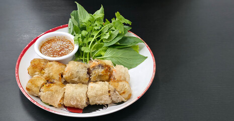 Crispy Vietnamese spring rolls served with fresh herbs and dipping sauce on a plate, ideal for traditional Asian cuisine themes