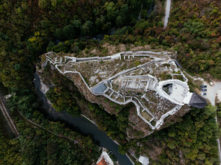 Medieval cliff-top fortress overlooking river and red-roofed town in Uzice, Serbia, with winding...