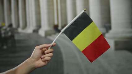 Caucasian man holding belgian flag inside old university building with large pillars in belgium...