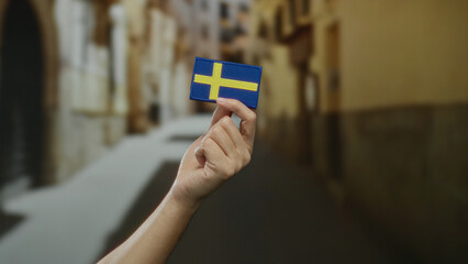 Man holding swedish flag in a city street, showcasing national pride with scandinavian emblem...