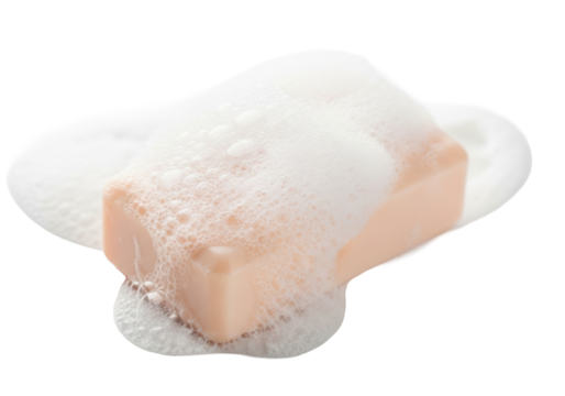 Pale peach rectangular soap bar covered in thick creamy white foam and delicate iridescent bubbles, diagonally on transparent background with copy space. Concept of purity and luxury hygiene