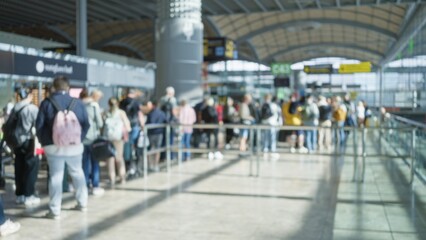 Crowd at airport terminal one with defocused people in blurred background and bokeh effect showcasing busy travel scene with diverse passengers waiting in queue.