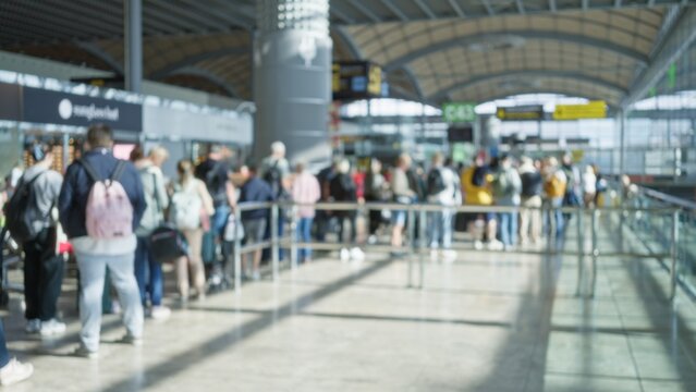 Crowd at airport terminal one with defocused people in blurred background and bokeh effect showcasing busy travel scene with diverse passengers waiting in queue.