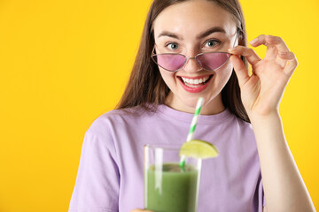 Woman with refreshing drink and straw on orange background
