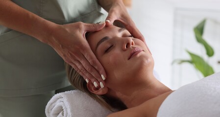 Beautiful woman receiving facial massage indoors, closeup