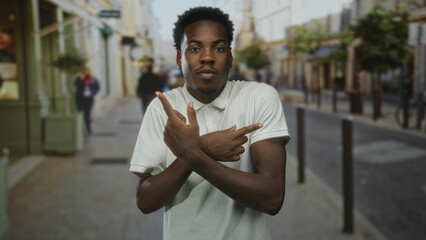 Man with crossed arms pointing fingers on city street lined with boutique shops and decorative...