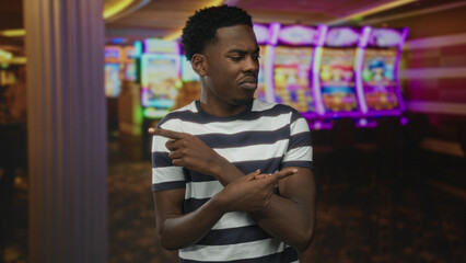 Man pointing finger at slot machine in casino under neon lights with a focused gaze on spinning...