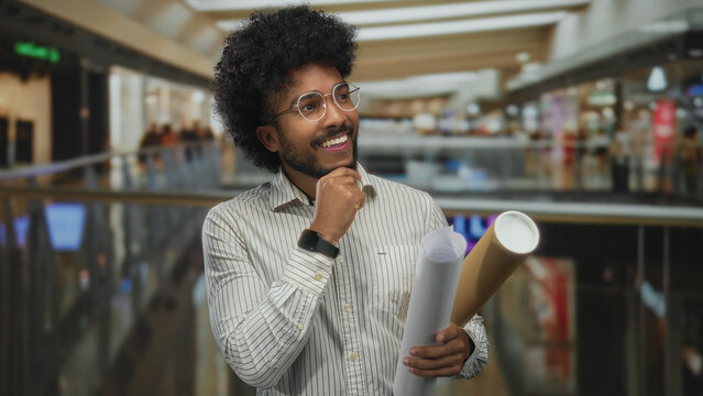 African american man holding blueprints in an indoor art gallery, appearing thoughtful and engaged. - Powered by Adobe