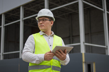 Male engineer. Tablet. Construction site. High quality photo.