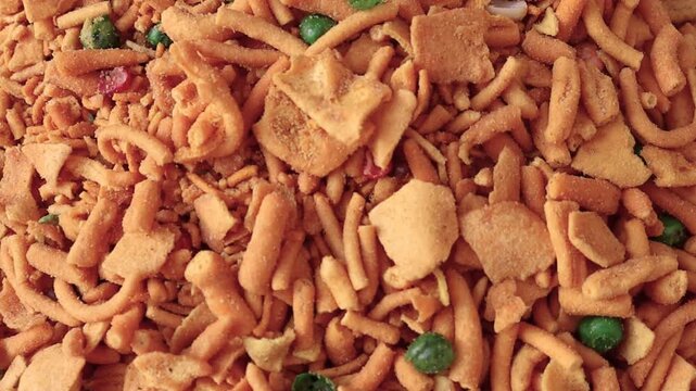 Snack mix close up macro footage golden brown fried noodles with green peas